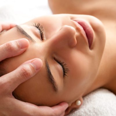 Close up head shot  of Woman having curative facial massage. Therapist applying pressure with thumbs on forehead.